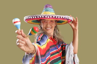 Arka planda marakas olan sombrero şapkalı olgun bir kadın. Meksika Ölüler Günü (El Dia de Muertos) kutlamaları