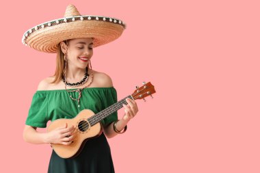 Şapkalı genç bir kadın pembe arka planda gitar çalıyor. Meksika Ölüler Günü (El Dia de Muertos) kutlamaları