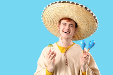 Mavi arka planda tekila ve marakas olan Sombrero 'lu Meksikalı genç bir adamın portresi.