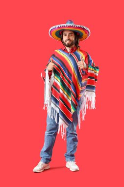 Sombrero ve pançolu yakışıklı genç adam kırmızı arka planda baş parmağını kaldırıyor.