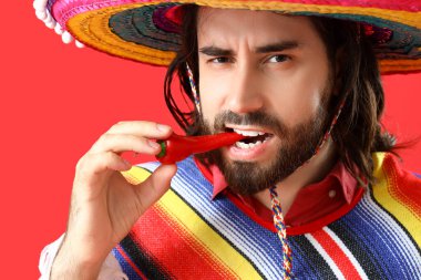 Kırmızı arka planda kırmızı biberli yakışıklı Meksikalı genç adam.