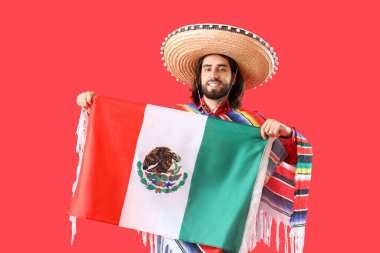 Kırmızı arka planda bayrağı olan yakışıklı Meksikalı genç adam.