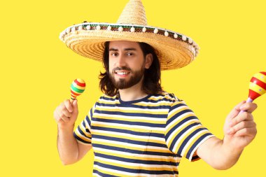 Sombrero 'daki yakışıklı Meksikalı genç adam ve sarı arka planda marakas.