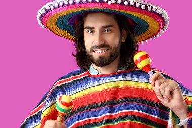 Sombrero, panço giymiş yakışıklı genç bir Meksikalı ve kırmızı arka planda marakas var.