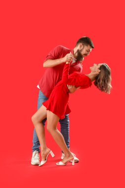 Mutlu çift kırmızı arka planda dans ediyor.