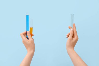 Mavi arka planda test tüpleri olan kadın eller.