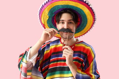 Pembe arka planda kağıt bıyıklı genç Meksikalı adam.