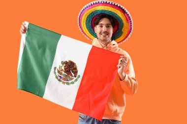 Turuncu arka planda bayrağı olan genç bir Meksikalı.