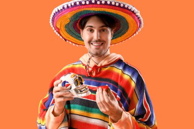 Kafatası boyalı ve arka planda kırmızı biber olan yakışıklı bir Meksikalı. Ölüler Günü Kutlaması