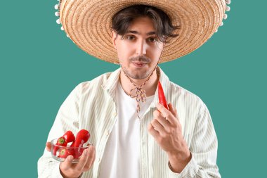 Yeşil arka planda kırmızı biberli genç Meksikalı adam.