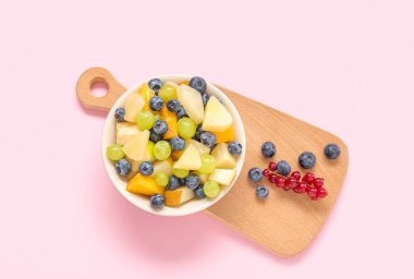 Pembe arka planda taze meyve salatası.