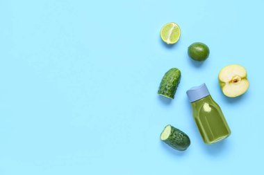 Açık mavi arka planda malzemeleri olan bir şişe sağlıklı yeşil meyve suyu.