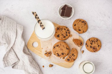 Çikolatalı kurabiyeler, beyaz arka planda şişe ve bir bardak süt.