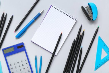 Gri arkaplanda kırtasiye malzemesi olan bir sürü renkli kalem