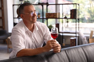 Yetişkin bir adam evde şarap tadıyor.