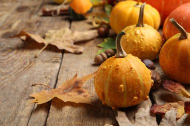 Kahverengi ahşap arka planda balkabağı ve sonbahar yapraklarıyla kompozisyon