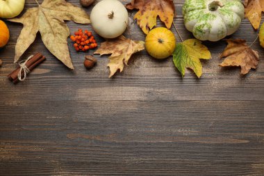 Kahverengi ahşap arka planda balkabağı ve sonbahar yapraklarıyla kompozisyon