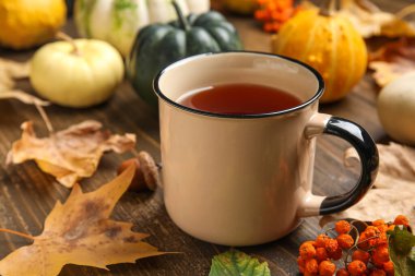 Kabaklı kompozisyon, bir fincan çay ve kahverengi ahşap arka planda sonbahar yaprakları