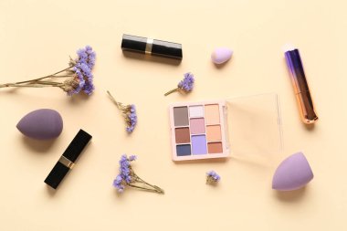 Makyaj ürünleri ve bej arka planda güzel çigila çiçekleri olan kompozisyon