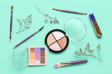 Makyaj ürünleri ve turkuaz arka planda güzel çiçekler içeren kompozisyon