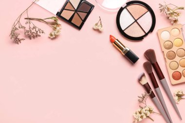 Makyaj ürünleri ve pembe arka planda güzel çigila çiçekleri olan kompozisyon