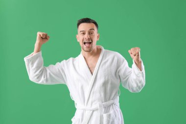 Yeşil arka planda bornozlu mutlu genç adam.