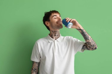Yeşil arka planda gazozu olan mutlu genç adam.