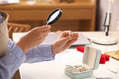 İş yerindeki süslemeleri inceleyen büyüteçle kadın mücevher tasarımcısı.