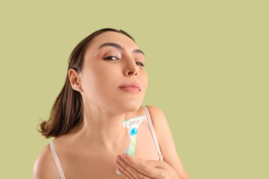 Yeşil arka planda jileti olan güzel genç bir kadın.