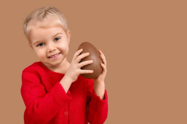 Kahverengi arka planda çikolatalı yumurtası olan tatlı küçük bir kız. Paskalya kutlaması