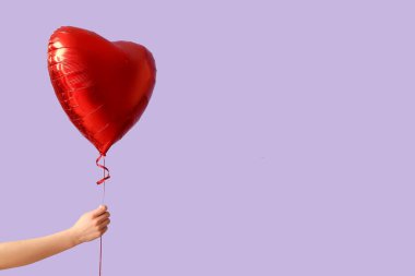 Leylak arka planında kalp şeklinde hava balonu olan bir kadın. Sevgililer Günü kutlaması