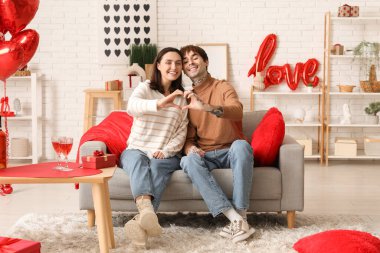 Evde elleriyle kalp yapan genç bir çift. Sevgililer Günü kutlaması