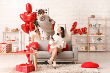 Genç adam sevgilisini sevgililer gününde evde karşılıyor.