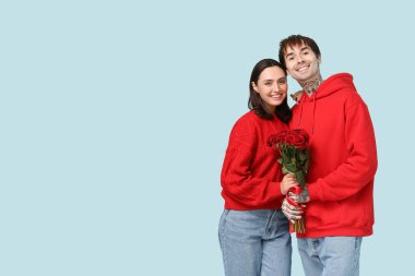 Mavi arka planda gül buketi olan genç bir çift. Sevgililer Günü kutlaması