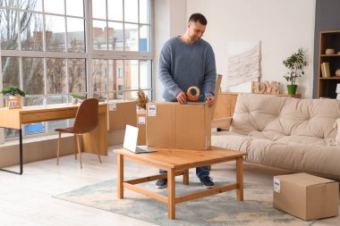 Genç adam evde bant ile paket paketi hazırlıyor.