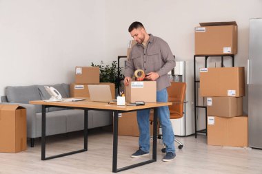 Depoda kasetle paket paketleyen bir erkek satıcı.