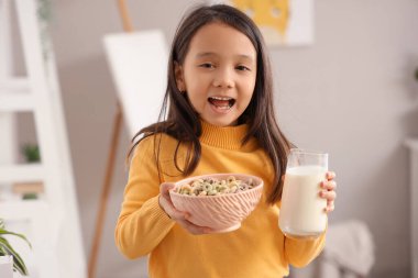 Evde mısır gevreği halkaları ve sütle küçük tatlı bir Asyalı kız.