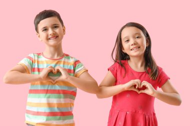 Şirin küçük çocuklar pembe arka planda kalp hareketi yapıyorlar. Sevgililer Günü kutlaması