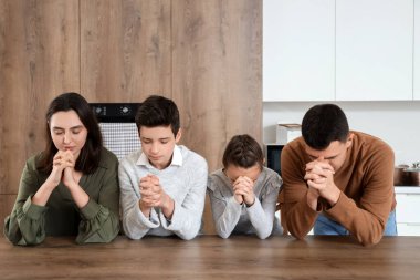 Aile mutfakta birlikte dua ediyor.