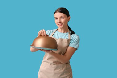 Mavi arka planda tepsisi ve saati olan güzel bir garson kız.