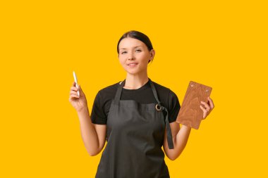 Sarı arka planda panosu ve kalemi olan güzel bir garson kız.
