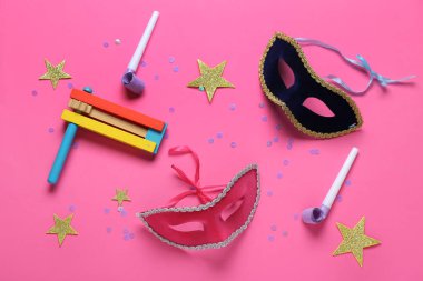 Çıngıraklı karnaval maskeleri, parti ıslıkları ve pembe arka planda Purim tatili için dekor.