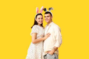 Sarı arka planda Paskalya tavşanı kulakları olan mutlu genç çift.
