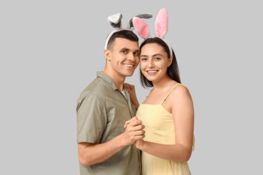 Gri arka planda Paskalya tavşanı kulakları olan mutlu genç çift.
