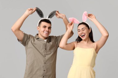 Gri arka planda Paskalya tavşanı kulakları olan mutlu genç çift.