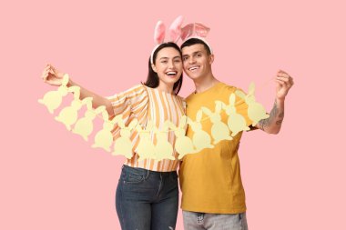 Paskalya tavşanı kulakları ve pembe arka planda çelengi olan mutlu genç çift.