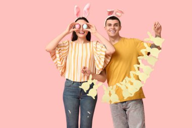 Paskalya tavşanı kulakları ve pembe arka planda çelengi olan mutlu genç çift.