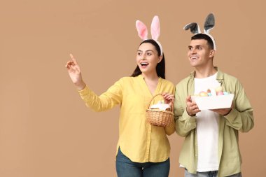 Paskalya sepetleri ve bej arka planda tavşan kulakları olan mutlu genç çift.