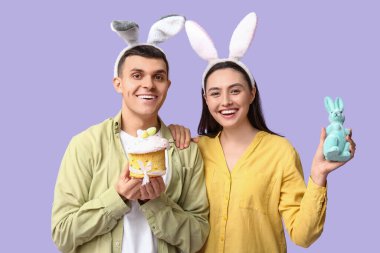 Paskalya pastası, oyuncak tavşan ve leylak arka planda tavşan kulaklı mutlu çift.