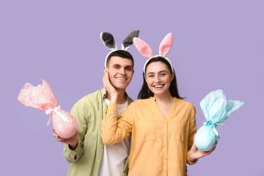 Paskalya hediyeleri ve leylak arka planda tavşan kulaklı mutlu genç çift.
